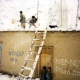 In a hamlet on the road between Nili and Yakawlang, at the first winter snowfall. A family clears off the snow of their house cob roof.
