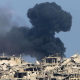 Nahr el Bared, 12 August 2007. Black smoke rises amid severely damaged buildings. Lebanese soldiers are being hampered in their fight against holed-up Islamist militants by the stench of putrefying corpses making the air unbreathable.