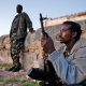 Two armed men from the local militia are looking towards the horizon in the light of the sunset, in Haafun, on the coast of Somalia.