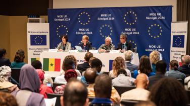 People at a press conference with EU branding in background