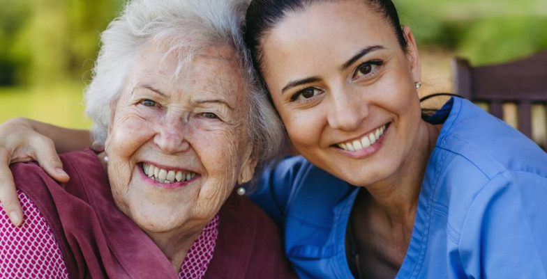 And elderly woman and her young woman care giver smiling happily.