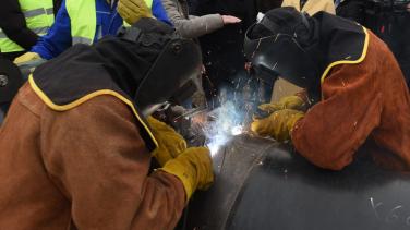 Two blacksmiths welding a pipe