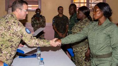 Uniformed man shakes hands with uniformed woman.