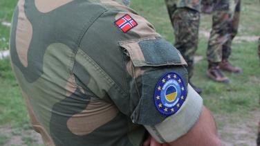 Over shoulder view of soldier wearing Norway and EU patches on uniform.