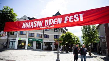 A large red banner strung across the open space between buildings that reads "KOLASIN OPEN FEST" 