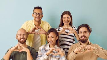 Five people (males and females) making a heart-shape wth their fingers in support of IWD Community's Inspire Inclusion Campaign
