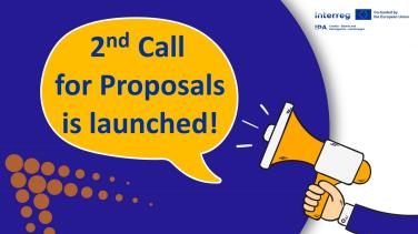 Visual for Interreg Call for Proposals showing a hand holding a megaphone