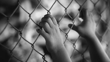 Hands holding fence