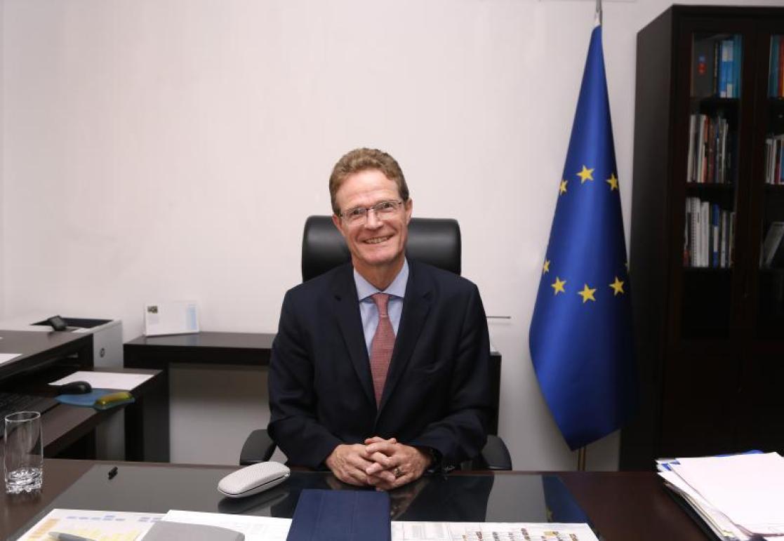 Ambassador Landrut  in his office with a EU flag behind him