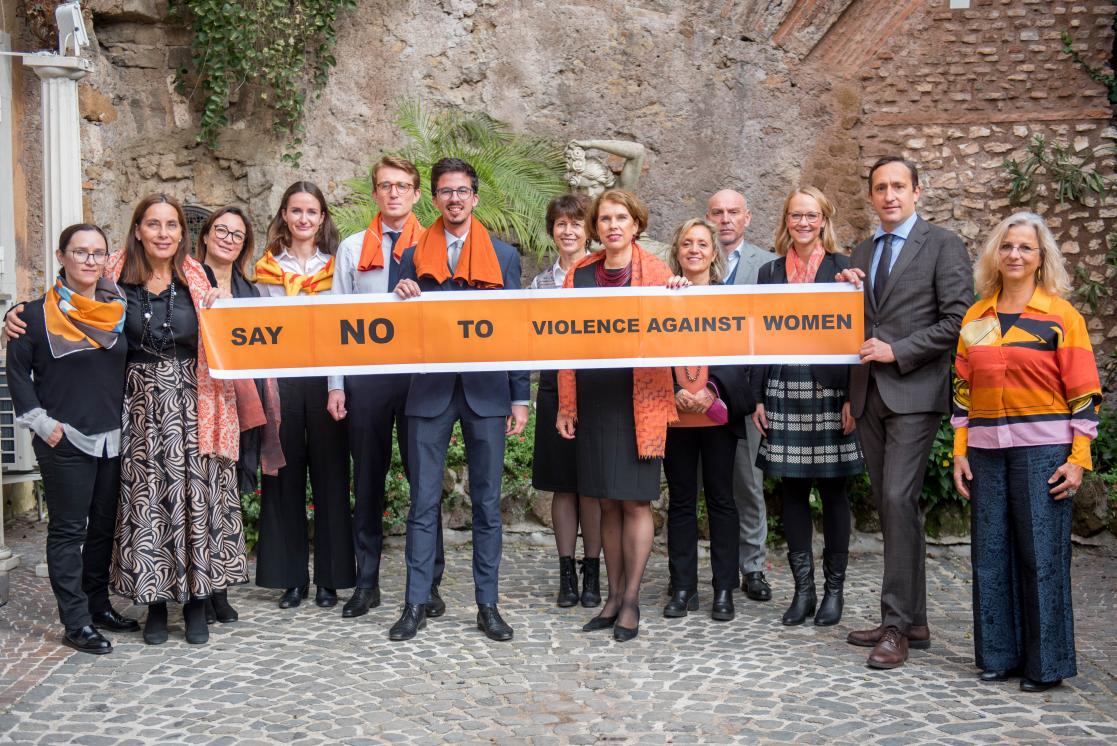 Group of people holding up a poster with the text "Say no to violence against women"