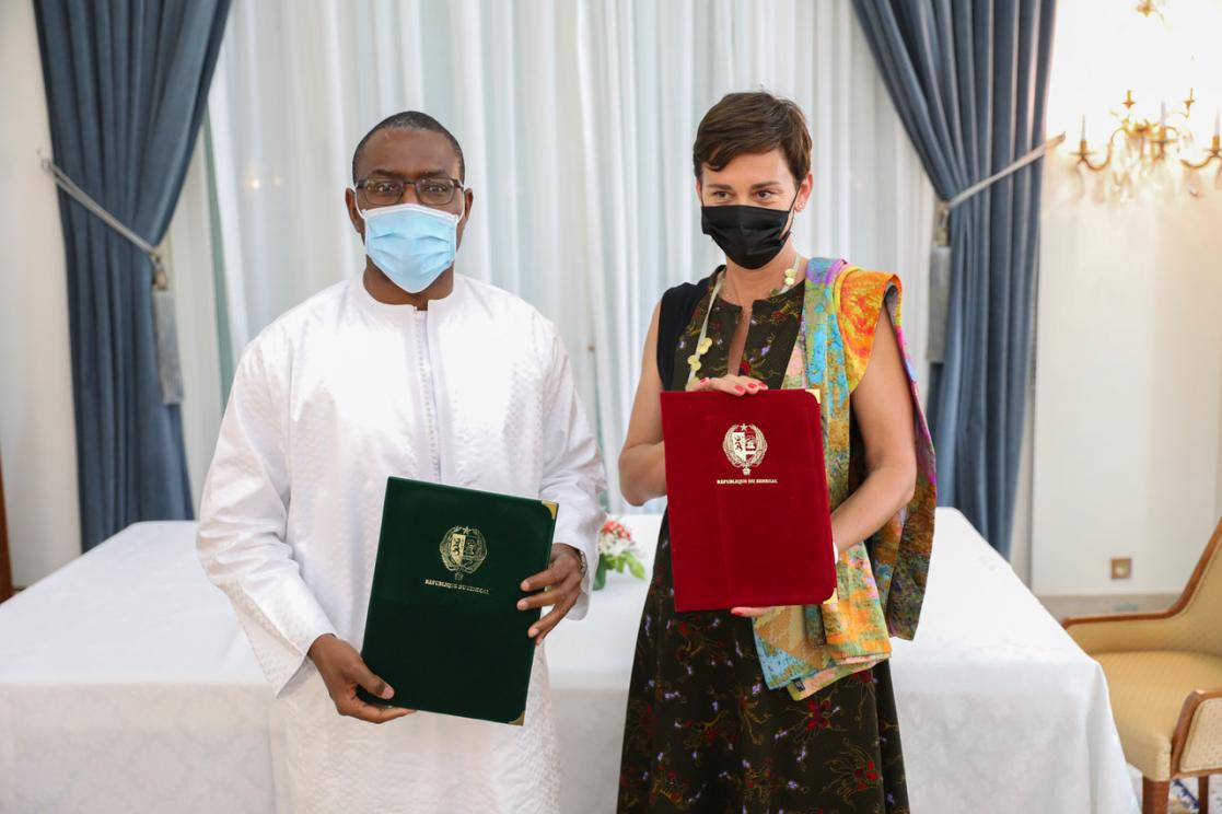 A man and a woman wearing a sanitary mask pose holding two red and green velvet folders