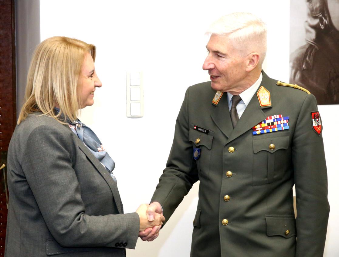A woman shaking hands with a man in general's uniform. 