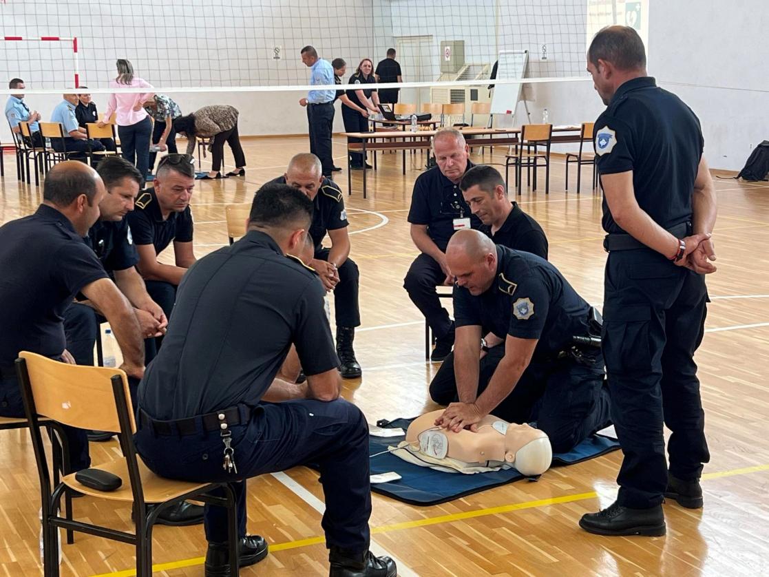 Uniformed men training in first aid inside a gym.