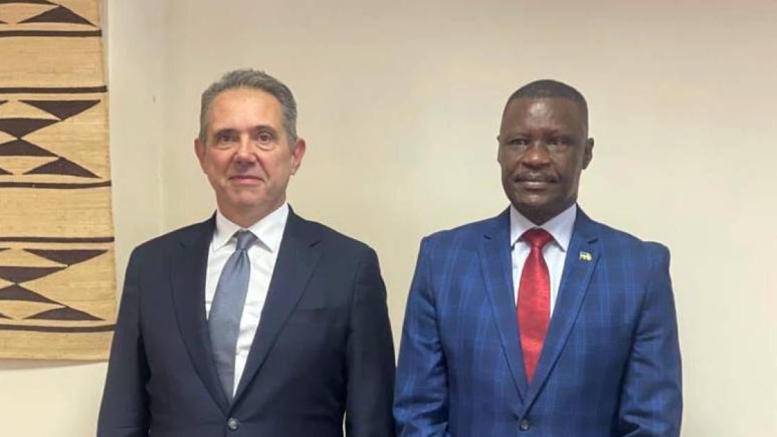 Two senior officials pose with wall art in the background.
