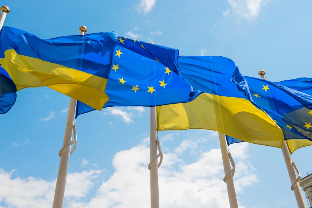 Several EU and Ukraine flags fly in the wind.