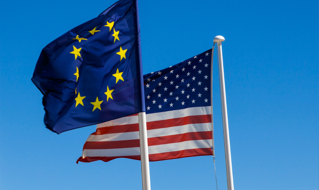 EU and US Flags flying in a clear blue sky