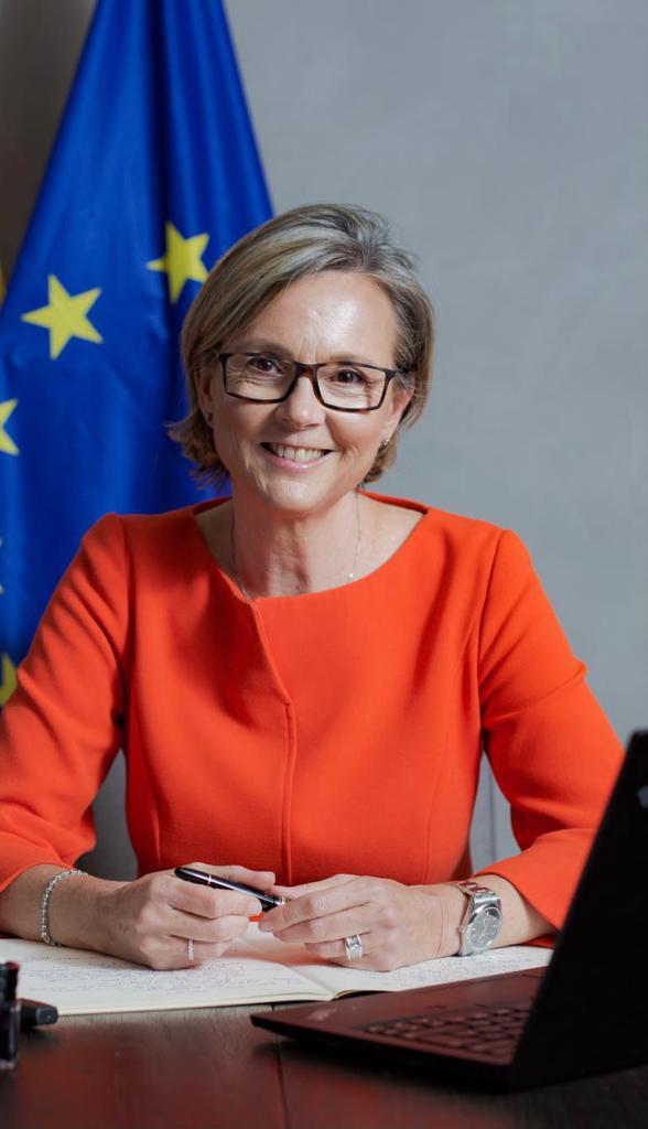 L'ambassadrice de l'union européenne au Maroc, assise dans son bureau, avec en arrière plan le drapeau de l'Union européenne