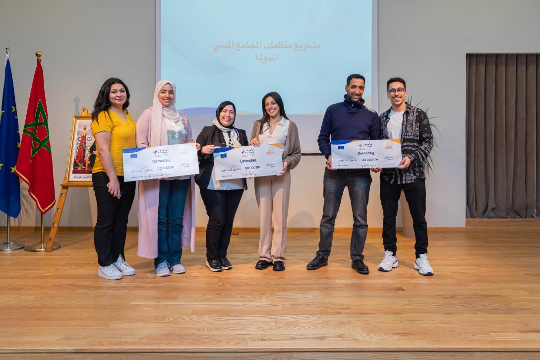 4 femmes et 2 hommes sur scène recevant des chèques gagnants lors d'un hackathon pour la société civile dans le cadre du projet Tamuri appuyé par l'UE au Maroc et mis en oeuvre par MCISE