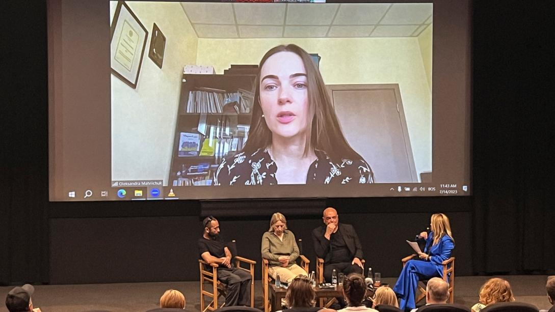 Oleksandra Matviichuk on a big screen in a conference theatre.