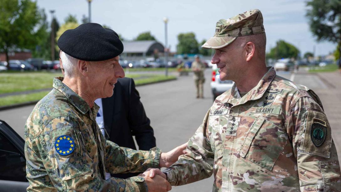 Two high ranking military officers meet and shake hands.