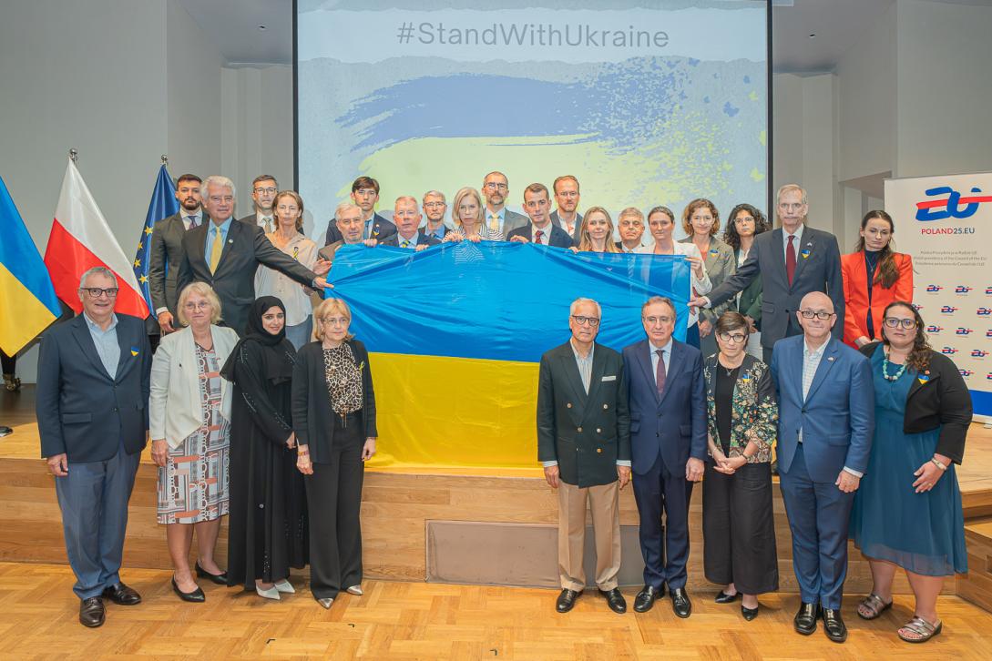 Group of ambassadors and diplomats holding Ukraine flag