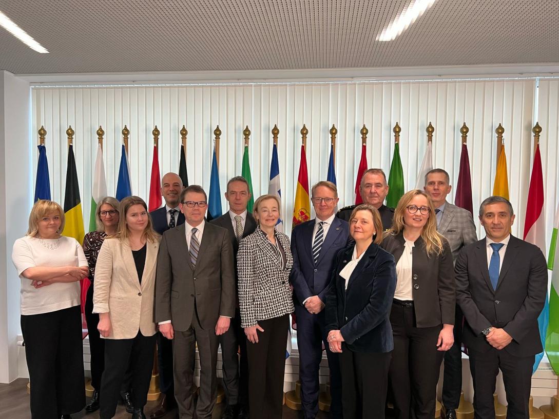 picture of 13 people in a group in front of multiple flags