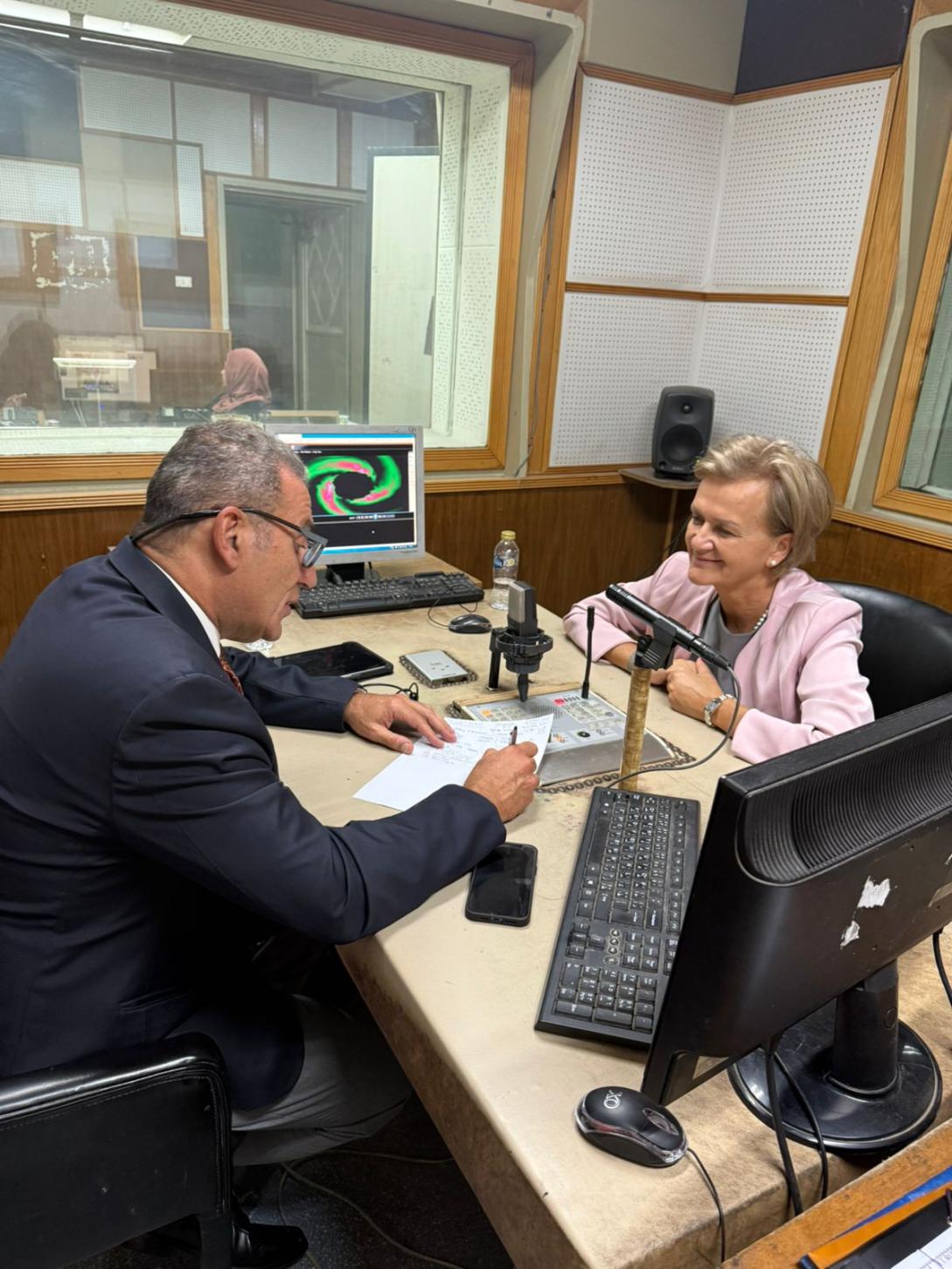 Two people sitting in a studio with microphones