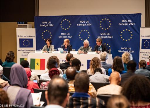 People at a press conference with EU branding in background