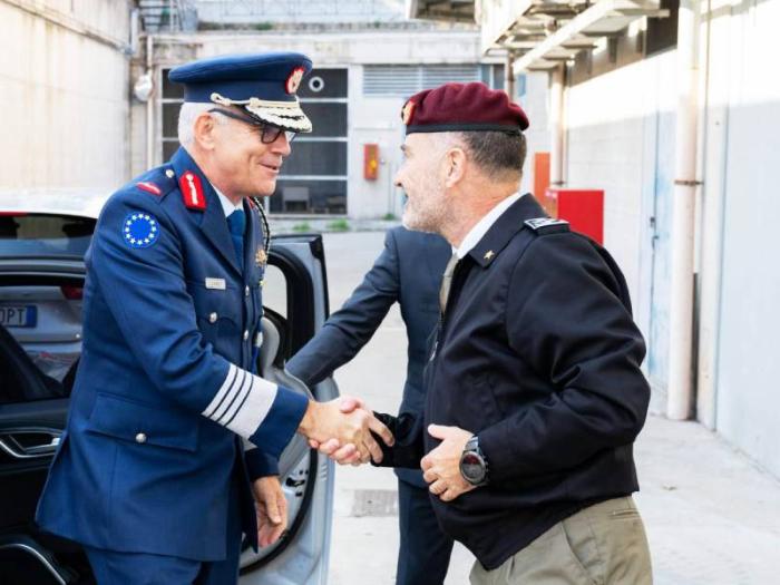 Two senior military officers greet each other with a handshake.