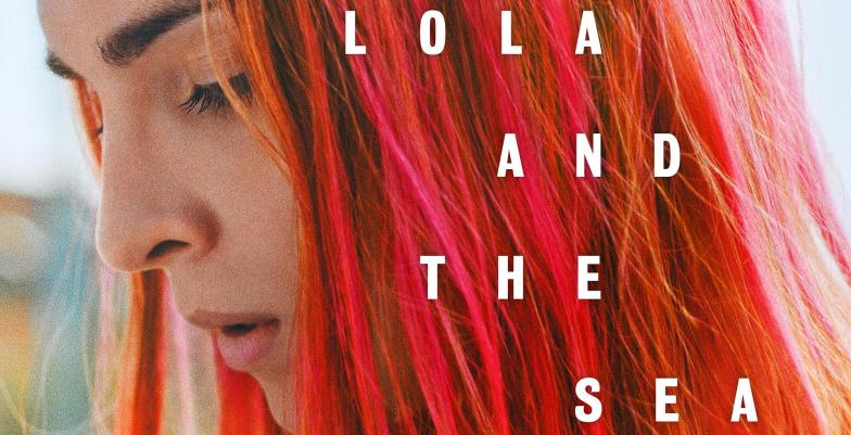 A young woman with red hair looks down with the words "Lola and the Sea" over top