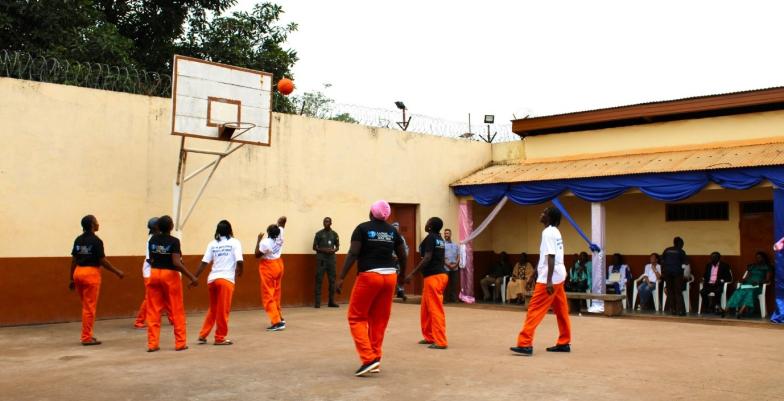 An excercise yard in a prison with prisoners playing sports.