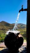 Water running from the tap with the mountains in the background